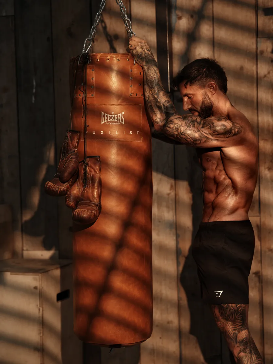 Side profile against a punch bag in striped window light
